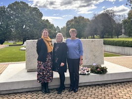 Three women standing in front of a memorial